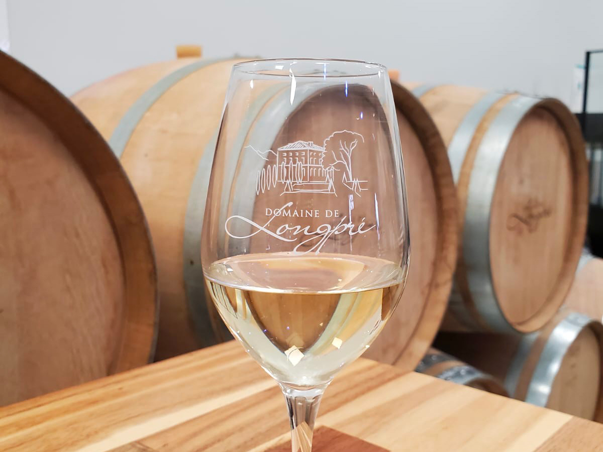 Les vins - Domaine de Longpré. Il y a un verre avec du vin blanc Domaine de Longpré à l'intérieur.